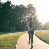 A person walking down a sidewalk in a park