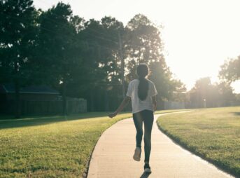 A person walking down a sidewalk in a park