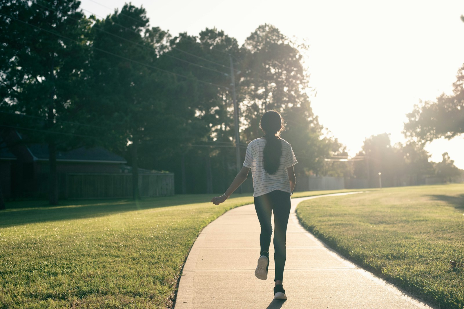 A person walking down a sidewalk in a park