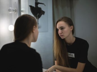 Portrait of a young woman reflecting in a mirror, creating a moody and introspective atmosphere.