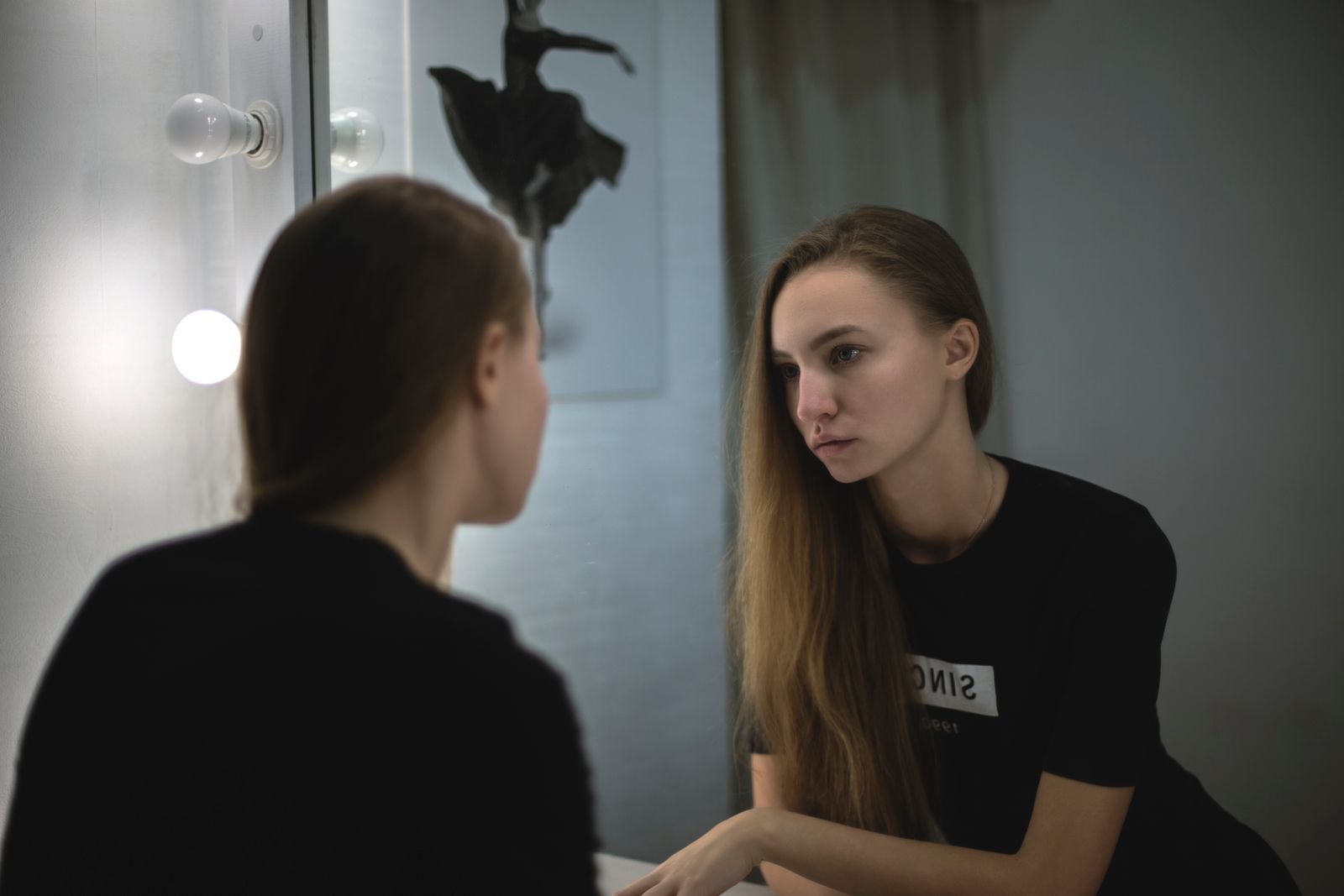 Portrait of a young woman reflecting in a mirror, creating a moody and introspective atmosphere.