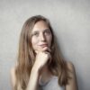 A thoughtful woman contemplates life in a simple portrait with a gray background.