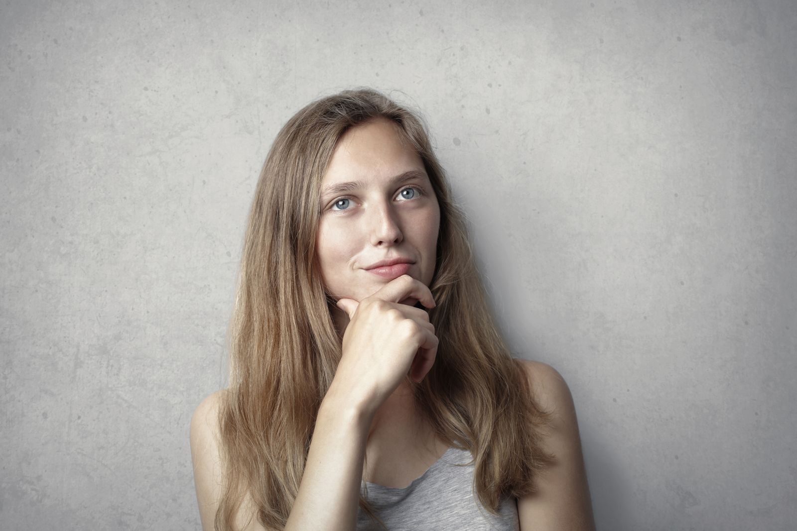 A thoughtful woman contemplates life in a simple portrait with a gray background.