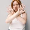Woman with red hair holding up hands with 'Yes' and 'No' written, expressing choice.