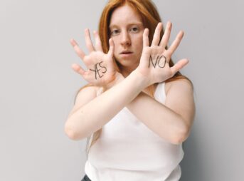 Woman with red hair holding up hands with 'Yes' and 'No' written, expressing choice.