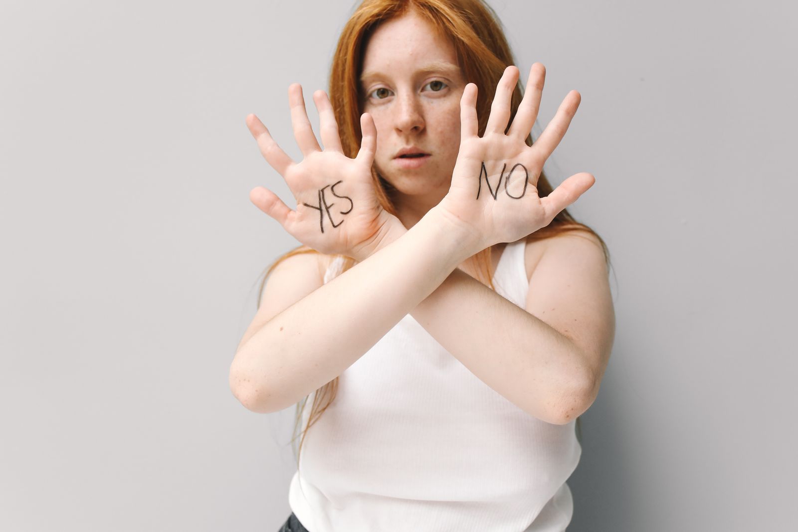 Woman with red hair holding up hands with 'Yes' and 'No' written, expressing choice.