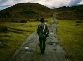 Person walking on a scenic countryside trail, embracing solitude and nature.
