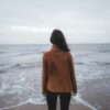 a woman standing on a beach looking out at the ocean