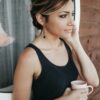 woman wearing black tank top holding mug