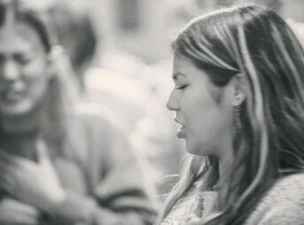 A black and white photo of a woman talking to another woman