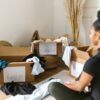 A woman organizing clothes into labeled boxes for donation and keeping.