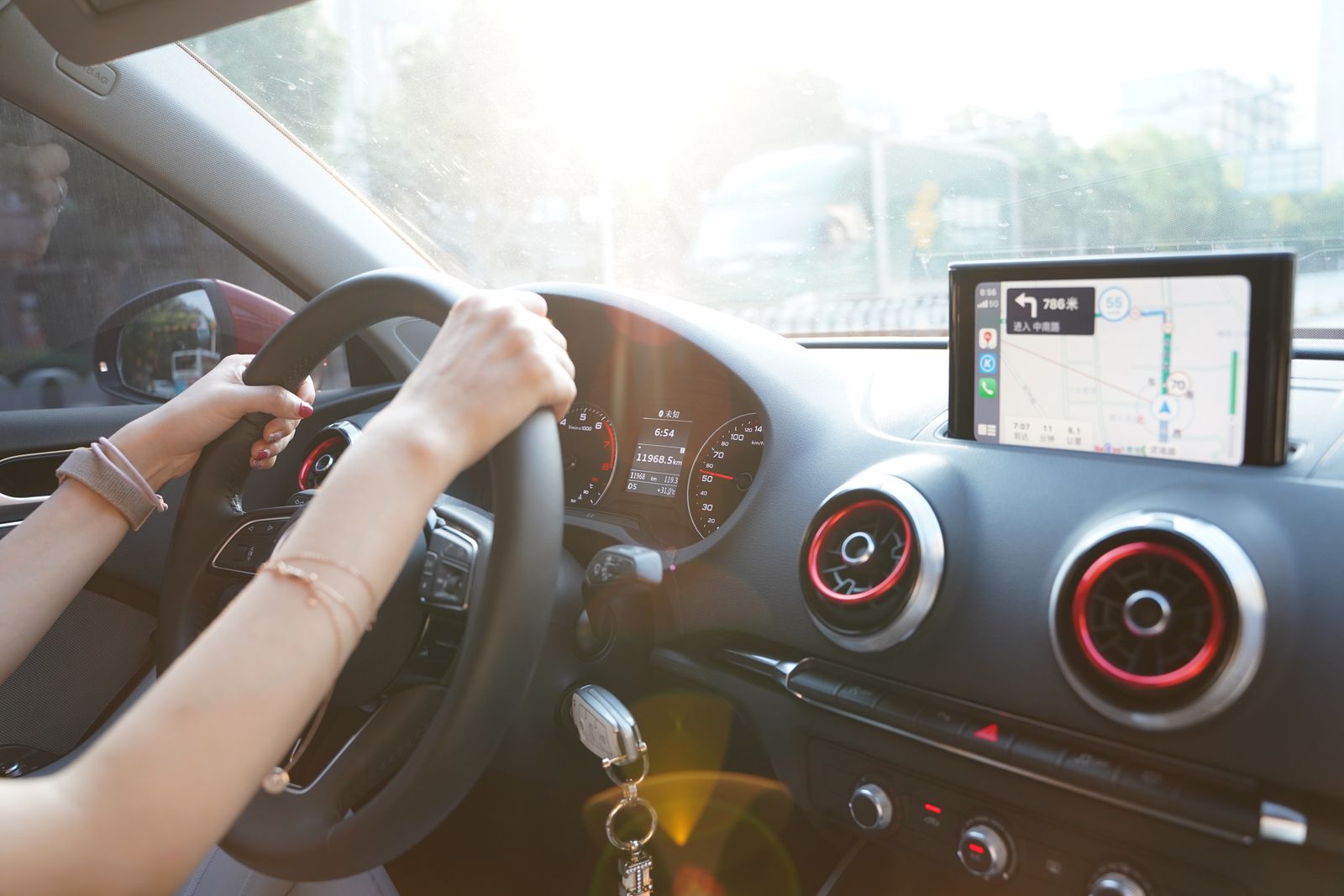 Hands on steering wheel using GPS navigation inside car during road trip.
