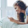 Young woman smiling while looking at her phone