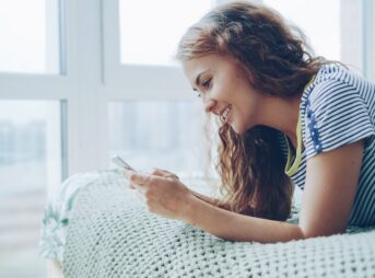 Young woman smiling while looking at her phone