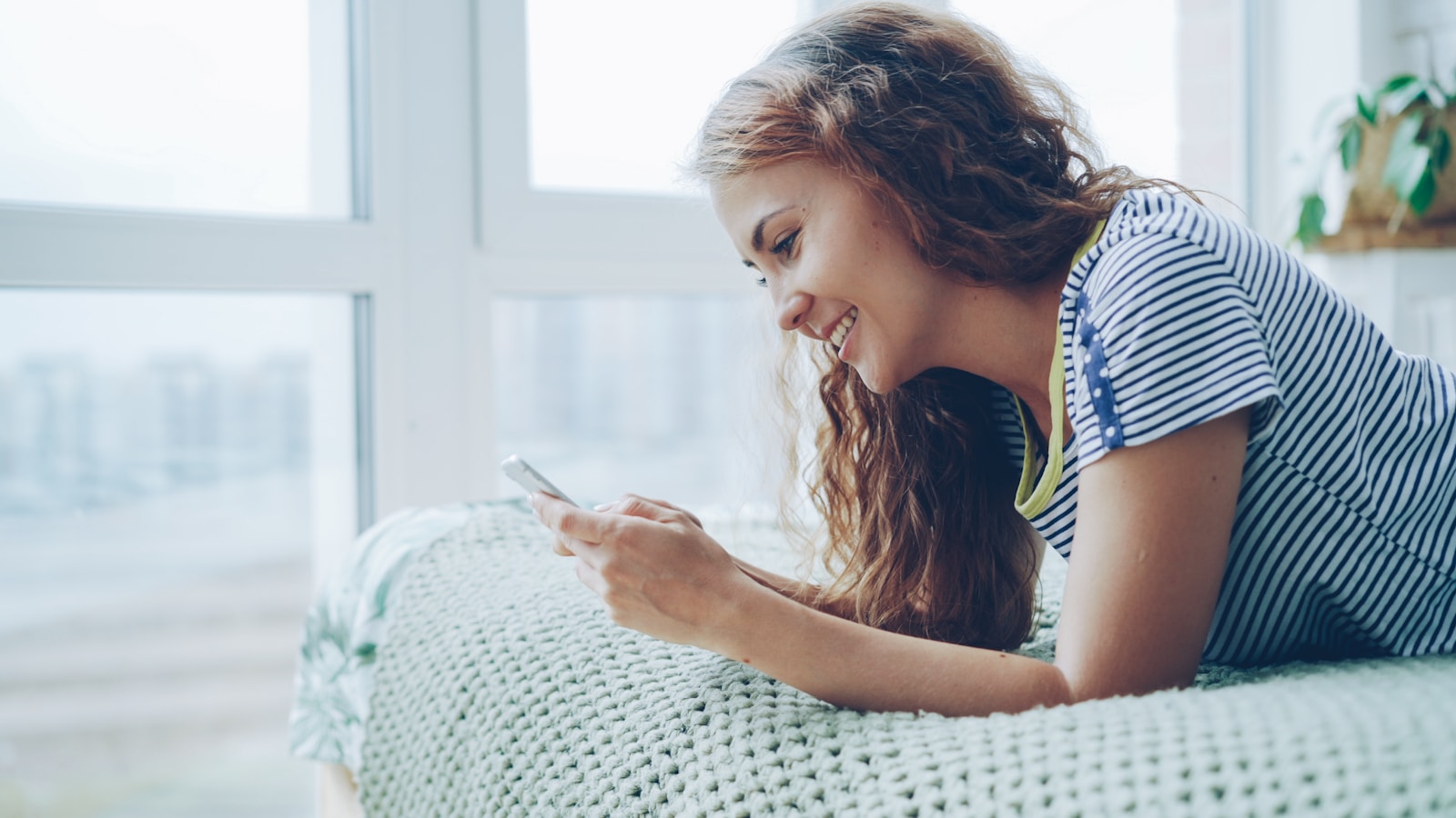 Young woman smiling while looking at her phone