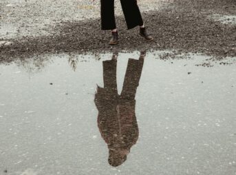 person in black pants and brown boots standing on gray concrete floor