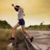 woman in white shirt and blue denim shorts standing on brown wooden dock during daytime