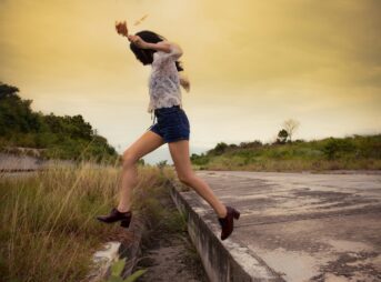 woman in white shirt and blue denim shorts standing on brown wooden dock during daytime