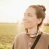 woman in brown long sleeve shirt standing on green grass field during daytime