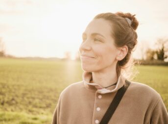 woman in brown long sleeve shirt standing on green grass field during daytime