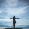 silhouette photography of woman standing on rock