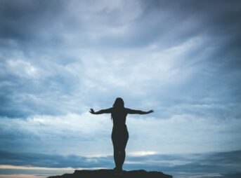 silhouette photography of woman standing on rock