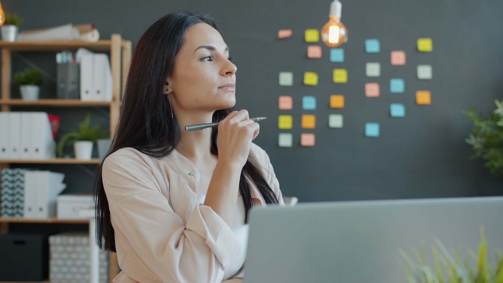 A woman thinking with a pen at her desk