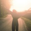 a person standing on a road with their arms outstretched