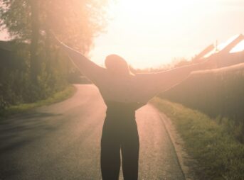 a person standing on a road with their arms outstretched
