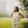 a woman standing in a park with her hands on her hips