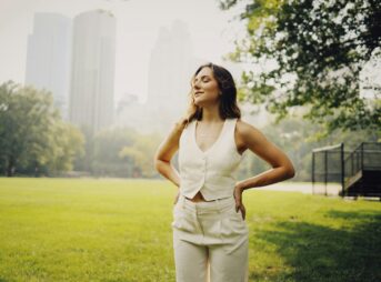 a woman standing in a park with her hands on her hips