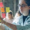 Woman analyzes sticky notes on glass