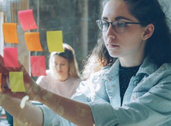 Woman analyzes sticky notes on glass