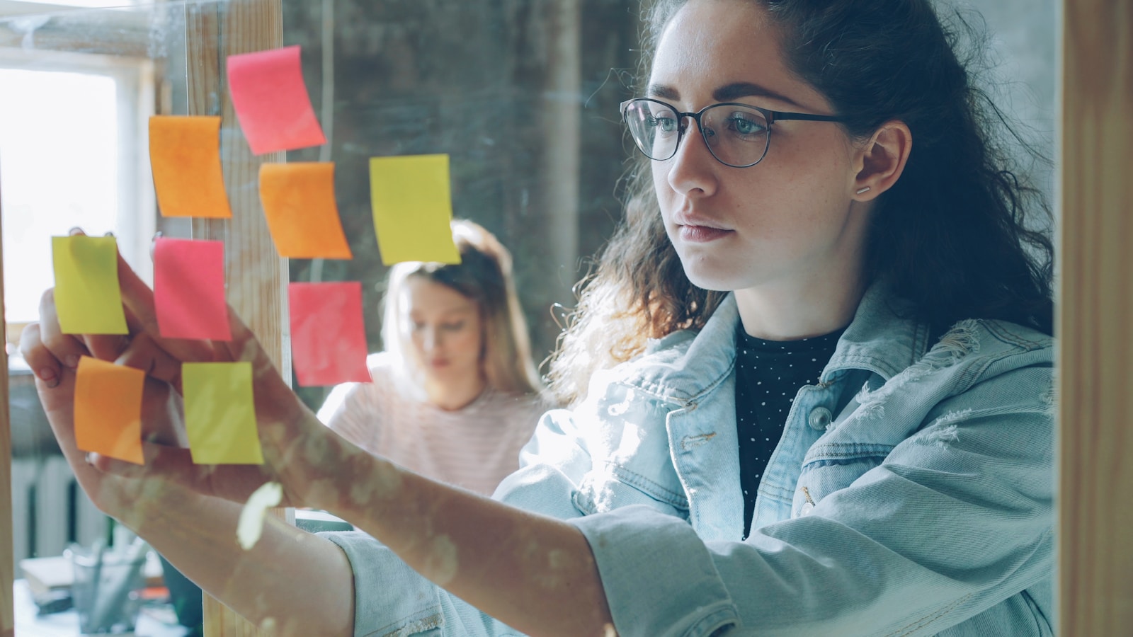 Woman analyzes sticky notes on glass