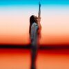 Woman reaching up against colorful sunset sky
