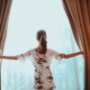 woman in black and white floral dress standing near window