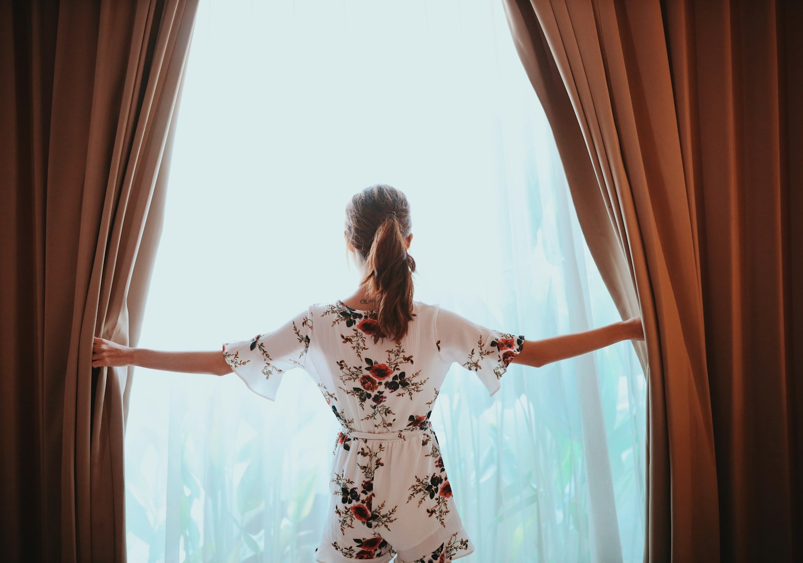 woman in black and white floral dress standing near window