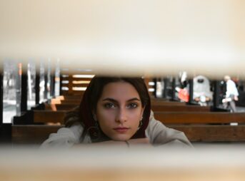 A woman sitting on a bench looking at the camera
