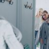 Two women try on a coat in a dressing room