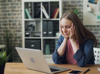 a woman sitting at a table with a laptop in front of her