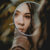 woman holding magnifying glass with brown liquid