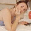 Woman lying on bed with phone and balloons