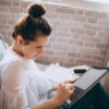 woman in white shirt holding black and silver laptop computer