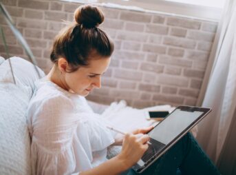 woman in white shirt holding black and silver laptop computer