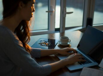 woman sitting beside table using laptop
