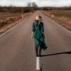 a woman in a green dress is walking down the road