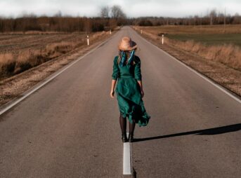 a woman in a green dress is walking down the road