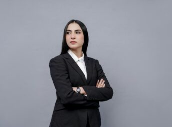 a woman in a business suit with her arms crossed