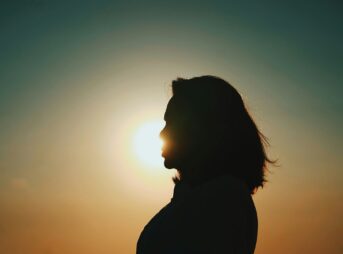 a silhouette of a person with the sun in the background