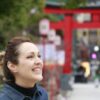 Woman smiling in front of a red shrine gate